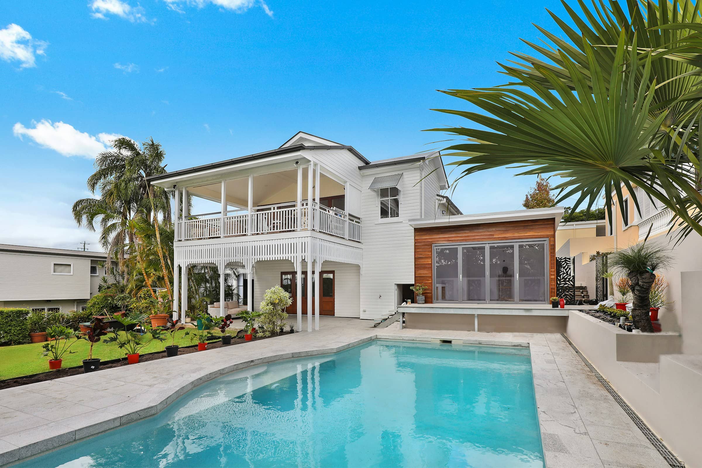 A two-story residential home with a covered porch and palm trees